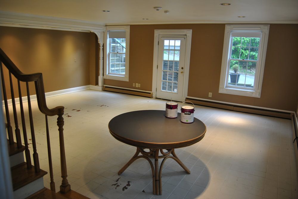 An empty room with brown walls, a staircase and a round table, before renovation