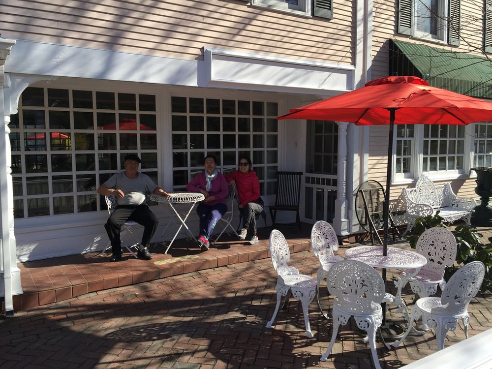 The brick patio with white garden chairs and red umbrellas in front of the Center