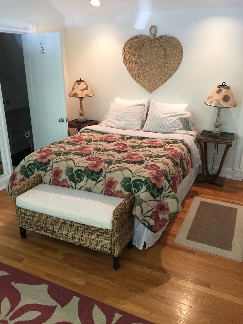 A bed with a floral quilt and a woven heart above it