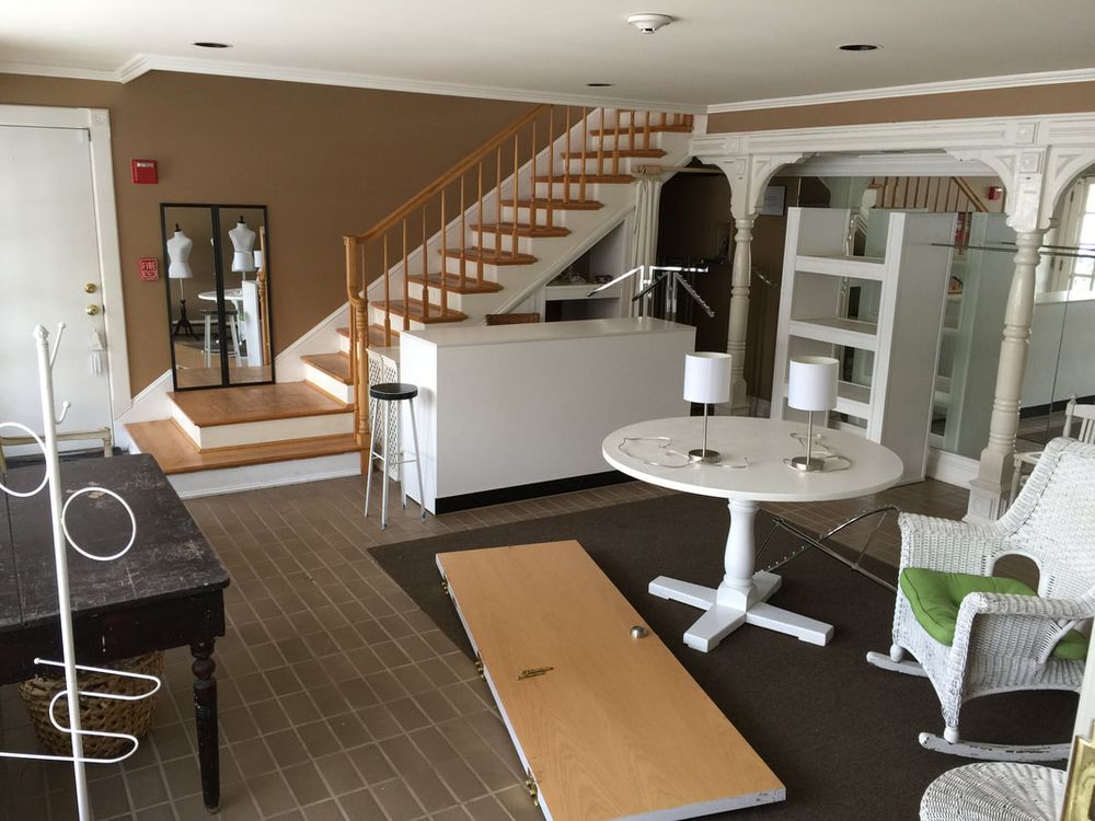 The finished workshop room with a white counter, round table and shelves under the staircase