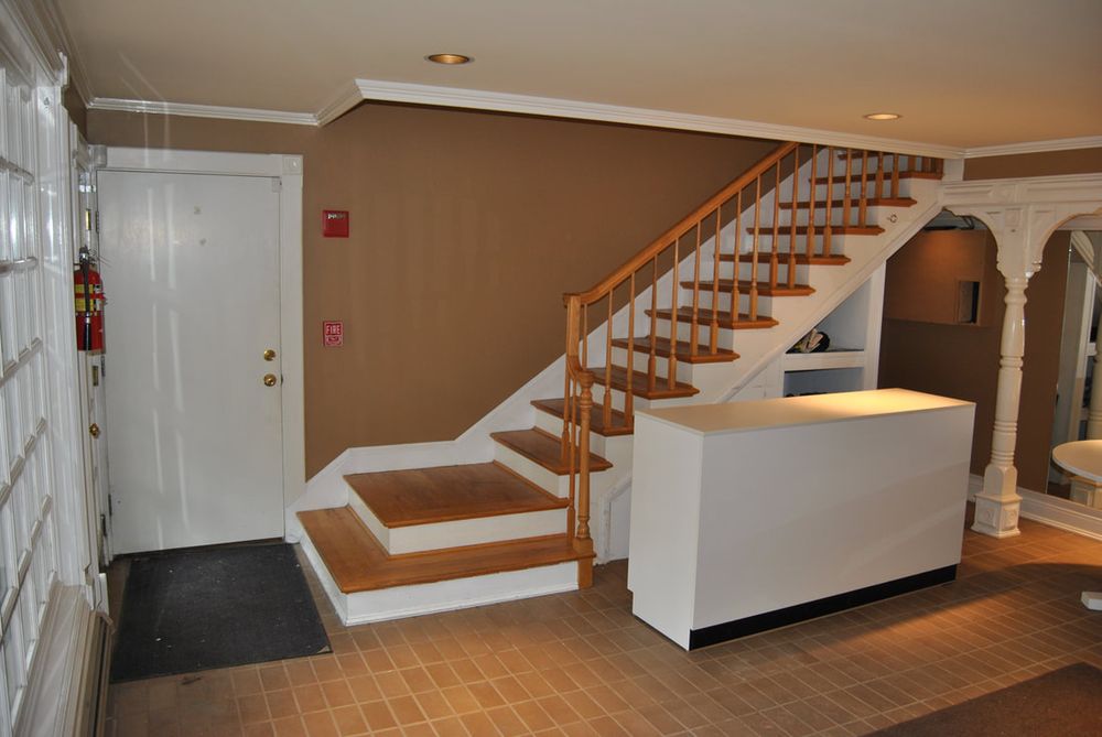 The workshop room before renovation, with brown walls and a white staircase