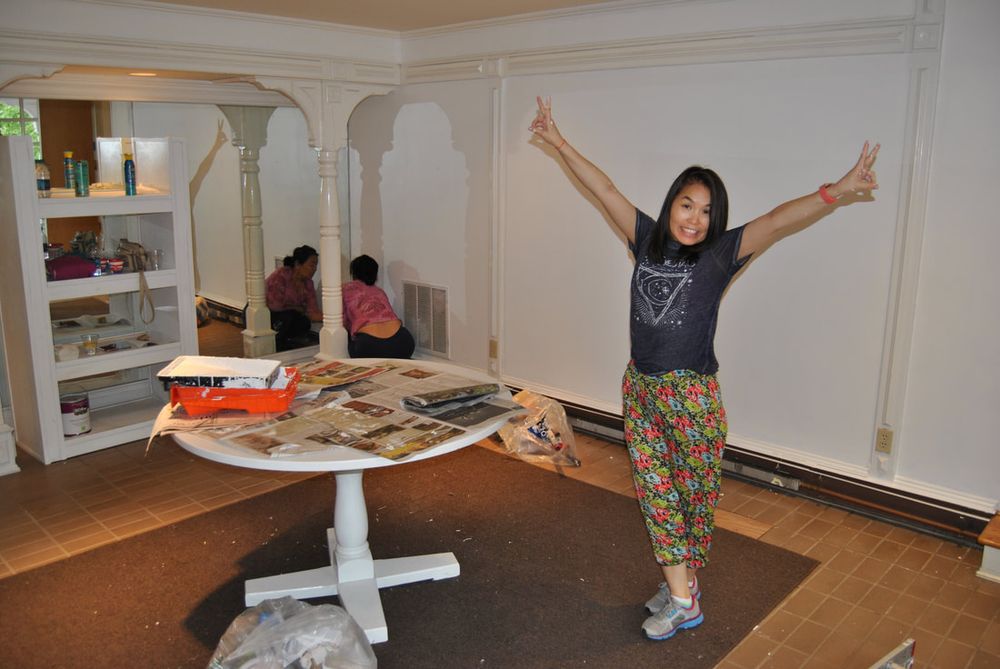 A freshly painted white room mid-renovation, with a helper cheering, arms raised